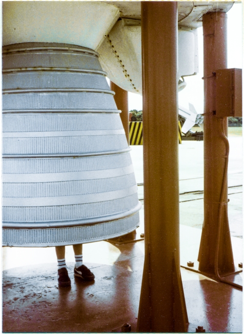 A very young Kai MacLaren stands inside the nozzle of the Rocketdyne LR79 MB-3 kerolox engine which propelled the Thor-Able rocket that is towering unseen directly above him, at the Air Force Space and Missile Museum at Cape Canaveral Air Force Station, Florida. Above and to the right of the nozzle, the enclosure which housed one of the two Rocketdyne LR101-NA vernier engines can be seen, along with just a very small bit of the nozzle of that vernier engine, protruding out to the right of the red support stanchion which holds up the Thor-Able. Below that, further in the distance, the cluster of four M5E1 solid-fuel motors along with lower control fins, on a Nike-Hercules surface-to-air defensive missile, can also be seen. Photograph by James MacLaren.